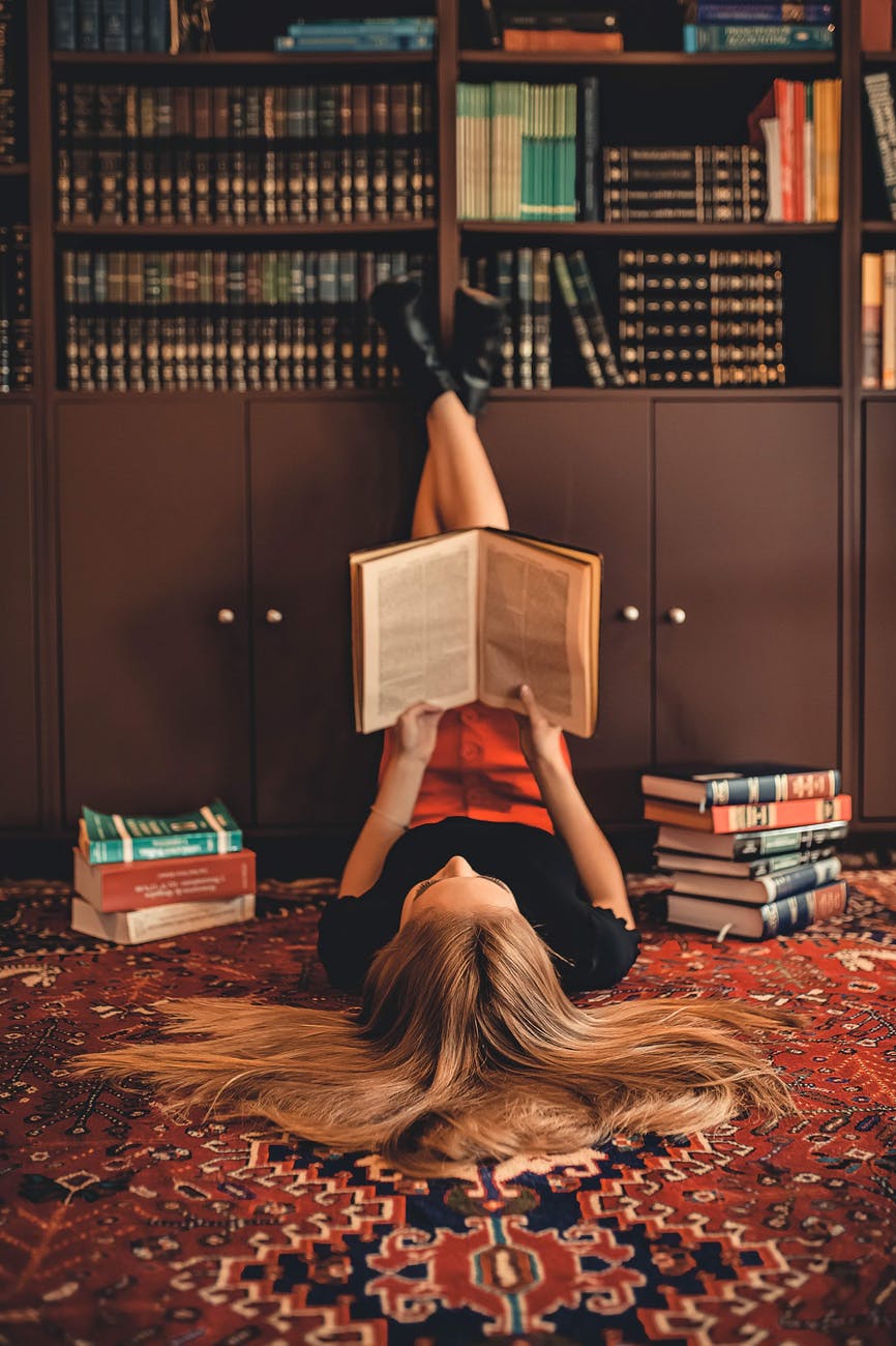 woman lying on area rug reading books
